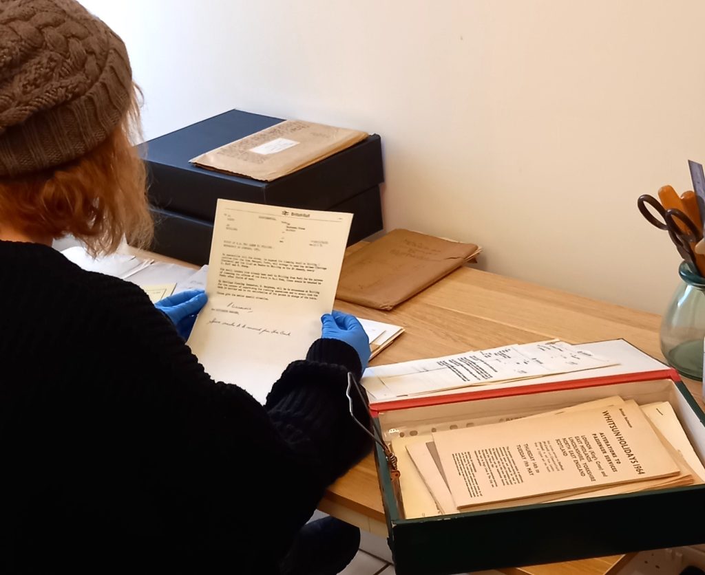 person with blue vinyl gloves handling document with more documents lying on table